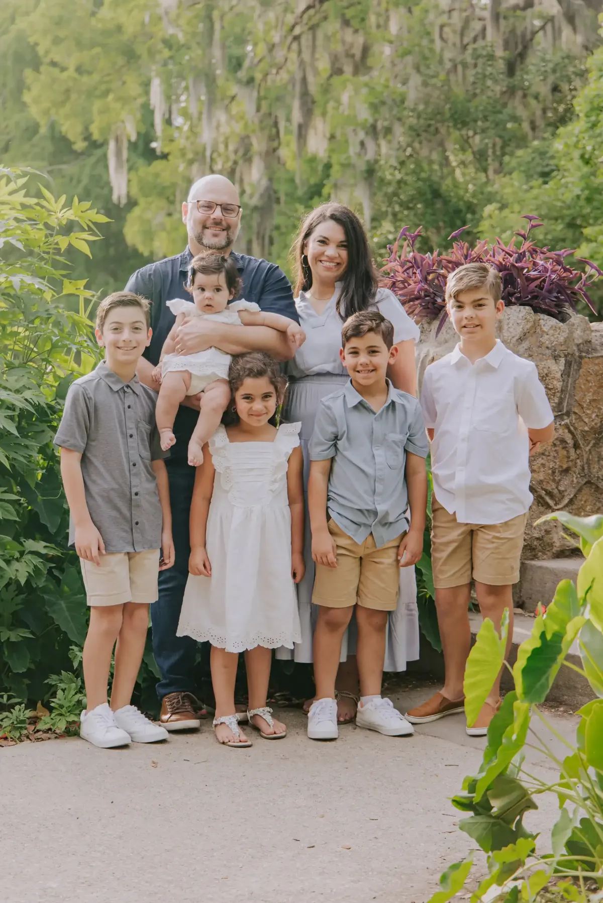 A family of seven posing together under Spanish-moss oaks